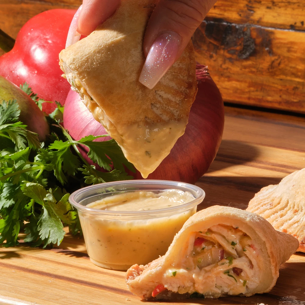 Passion Chicken empanada cut open with mango salsa and passion fruit sauce
